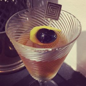 An image of the Tailspin Cocktail cocktail submitted by n0tquitethere that contains London Dry Gin, Sweet Vermouth, Green Chartreuse, Orange Bitters, Lemon and Cocktail Cherry